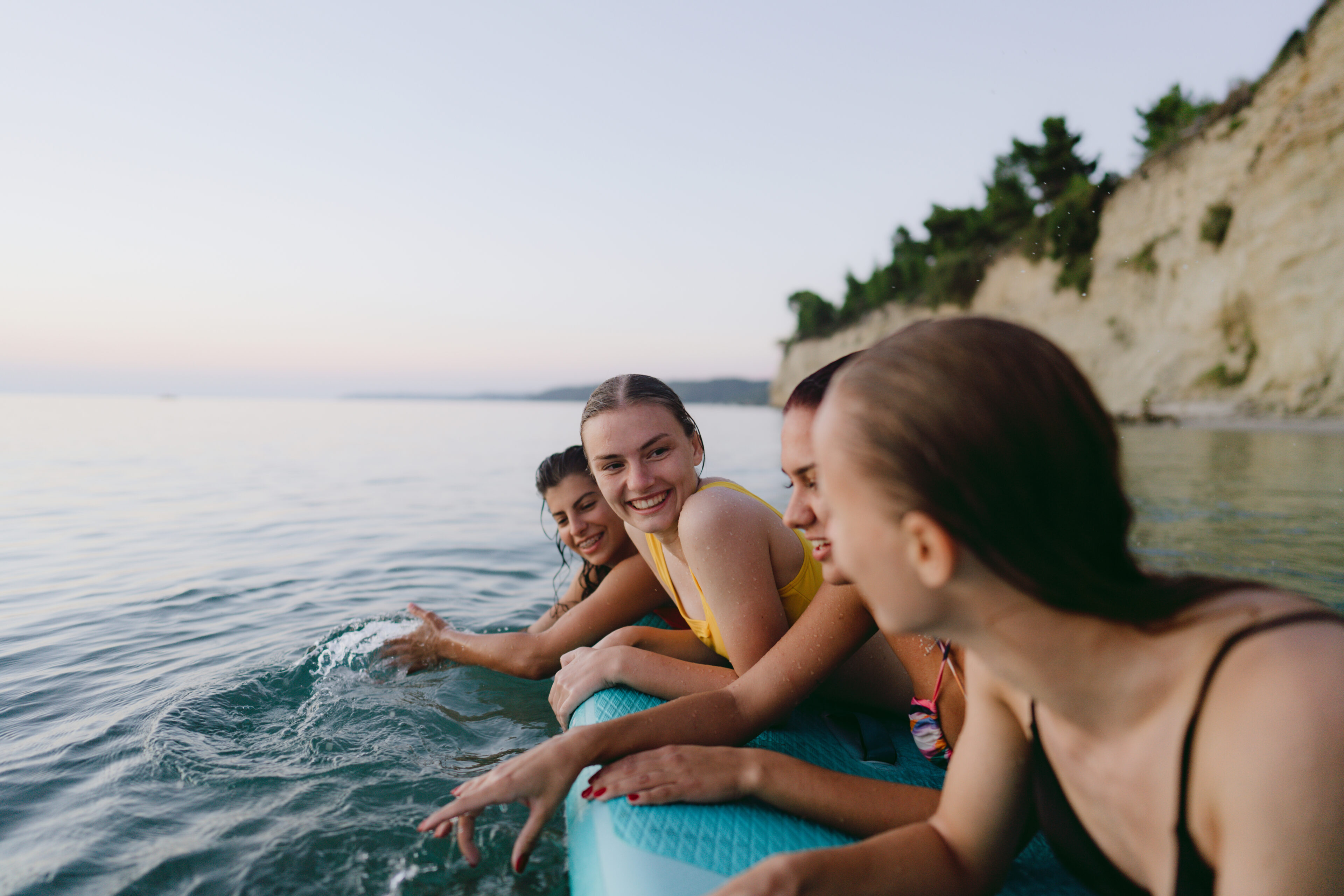 Photo of couple of young women SUP paddle boarding on the sea at sunset